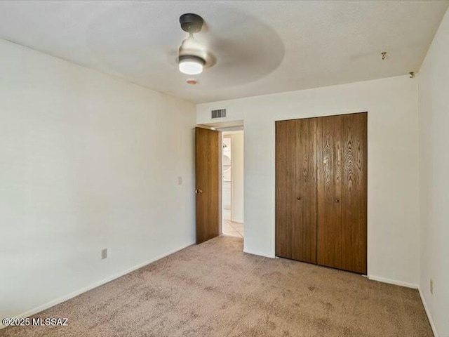 unfurnished bedroom featuring ceiling fan, light colored carpet, and a closet