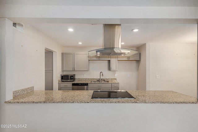 kitchen with sink, gray cabinets, appliances with stainless steel finishes, island range hood, and light stone countertops