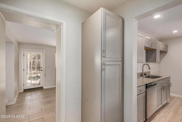 kitchen featuring gray cabinets, dishwasher, sink, and light stone countertops