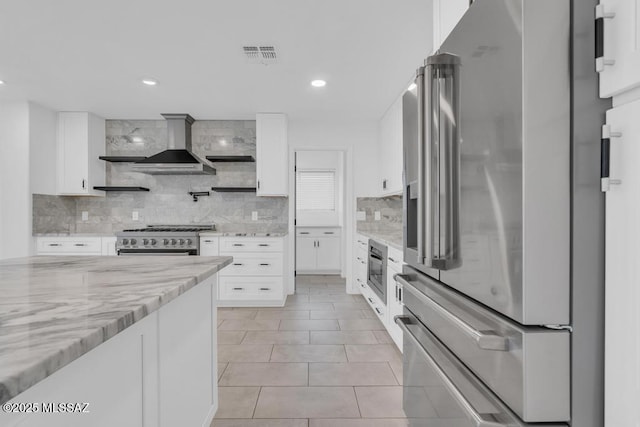 kitchen with tasteful backsplash, high end appliances, light stone countertops, and white cabinets