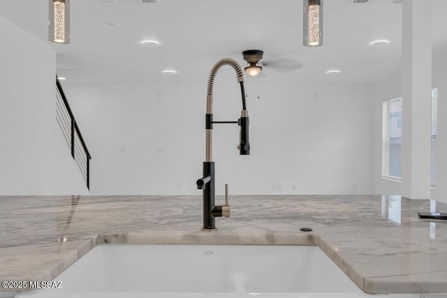 interior details with pendant lighting, sink, and light stone countertops