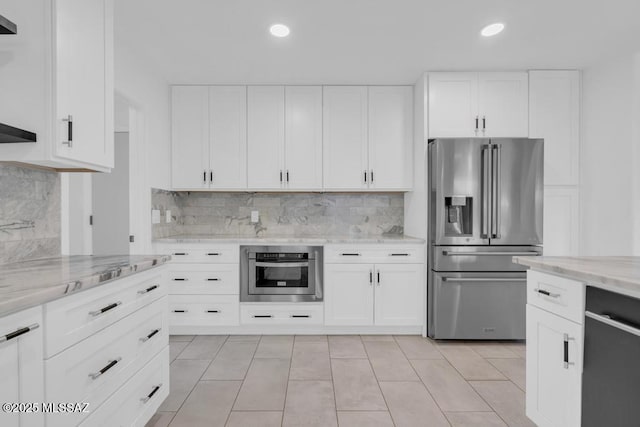 kitchen with light stone counters, appliances with stainless steel finishes, backsplash, and white cabinets