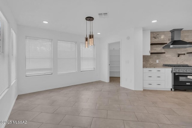 kitchen featuring wall chimney range hood, white cabinetry, high end range, decorative backsplash, and decorative light fixtures