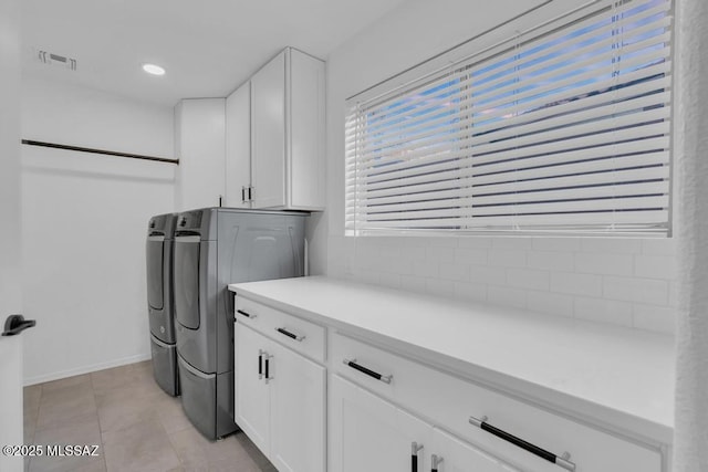 clothes washing area with cabinets, washer and dryer, and light tile patterned floors