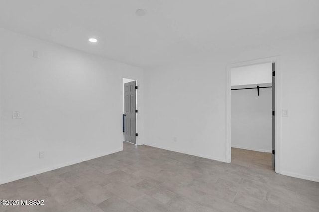 unfurnished bedroom with a walk in closet and a barn door