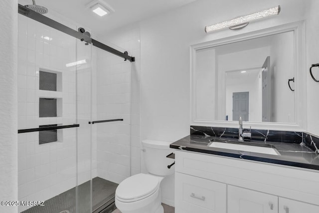 bathroom with vanity, toilet, and a shower with door