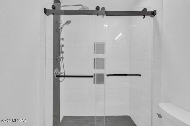 bathroom with a shower with shower door and toilet