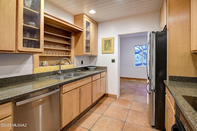 kitchen with light tile patterned floors, stainless steel appliances, glass insert cabinets, a sink, and baseboards