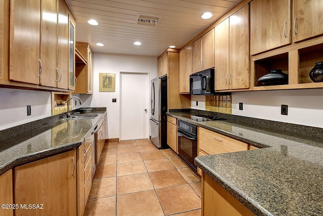 kitchen featuring light tile patterned floors, visible vents, dark stone countertops, black appliances, and a sink