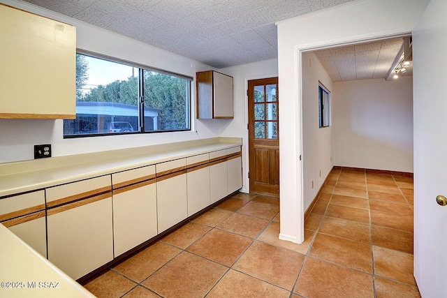 kitchen featuring white cabinets, light countertops, baseboards, and light tile patterned floors