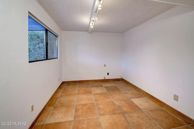 empty room with rail lighting and baseboards