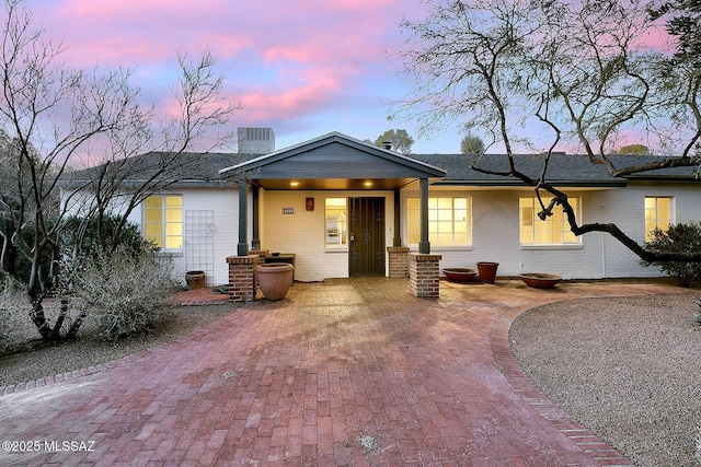 view of front of home with brick siding and roof with shingles