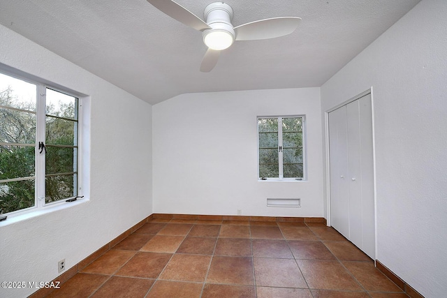 spare room with vaulted ceiling, a textured ceiling, a ceiling fan, and baseboards