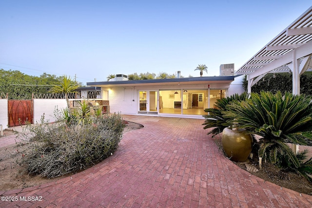 rear view of property featuring fence, a patio, and a pergola