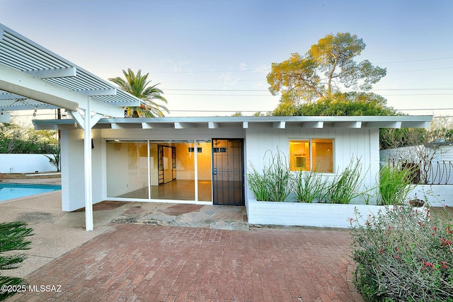 rear view of house with a fenced in pool, a patio area, fence, and a pergola