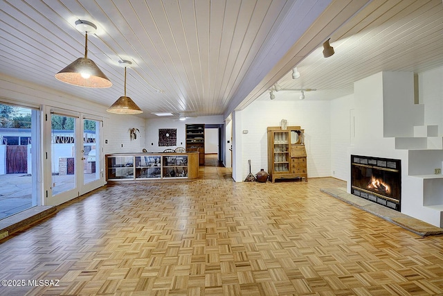 unfurnished living room with wood ceiling, a glass covered fireplace, and rail lighting