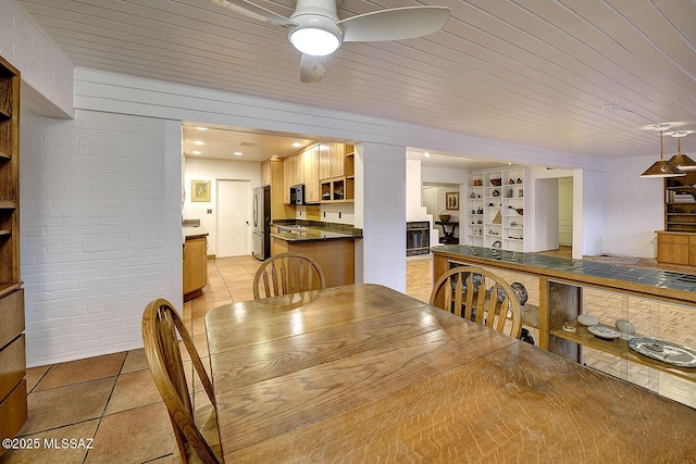 dining room featuring built in features, light tile patterned floors, wood ceiling, ceiling fan, and brick wall