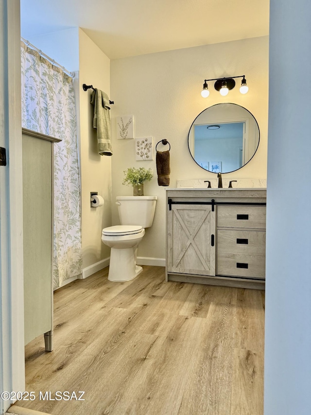 full bathroom with toilet, vanity, baseboards, and wood finished floors