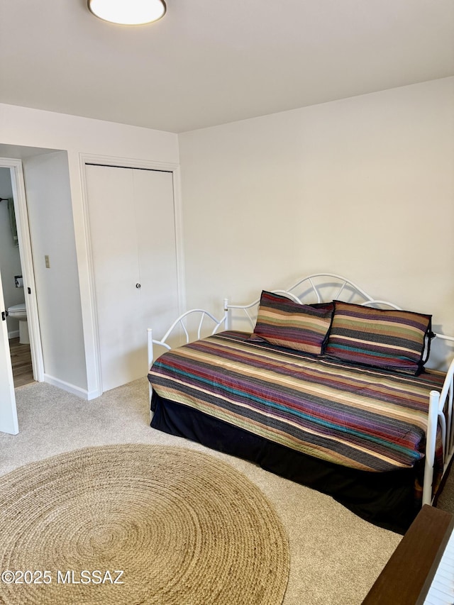 carpeted bedroom featuring a closet and baseboards