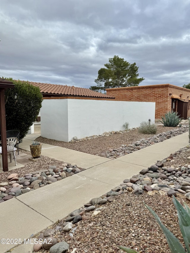 view of side of home with a patio, fence, and brick siding