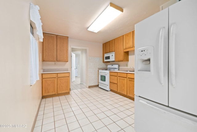 kitchen with light tile patterned flooring, white appliances, and sink