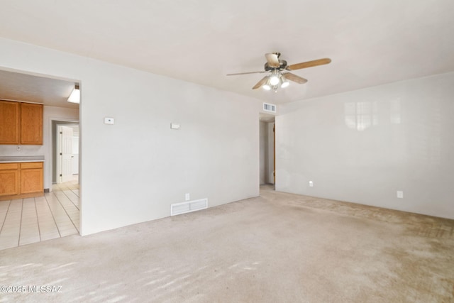 empty room with ceiling fan and light carpet