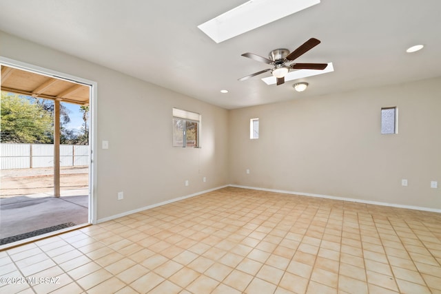 spare room with light tile patterned floors, a skylight, and ceiling fan