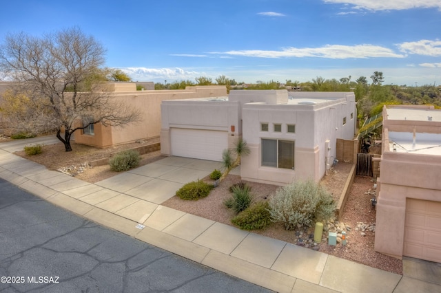 southwest-style home with concrete driveway, an attached garage, fence, and stucco siding