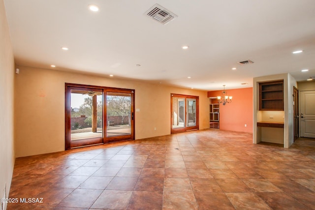 unfurnished living room with built in shelves and a chandelier