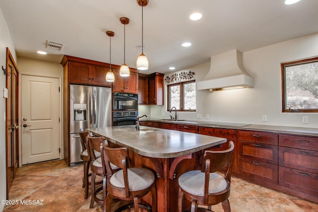 kitchen with premium range hood, pendant lighting, sink, black appliances, and a center island with sink