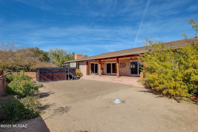 back of house with a hot tub and a patio