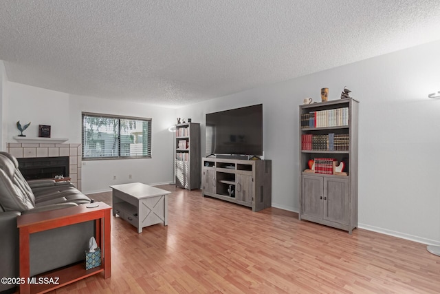 living room with hardwood / wood-style floors, a tile fireplace, and a textured ceiling