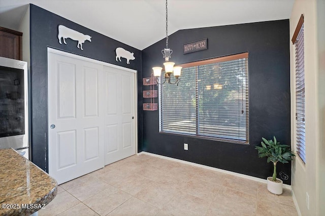 dining room featuring lofted ceiling, light tile patterned floors, and an inviting chandelier