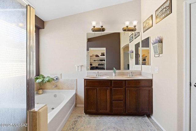 bathroom with a healthy amount of sunlight, vanity, a bathing tub, and tile patterned flooring