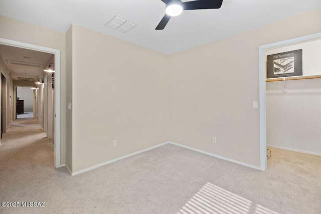 unfurnished bedroom featuring a walk in closet, light colored carpet, a closet, and ceiling fan