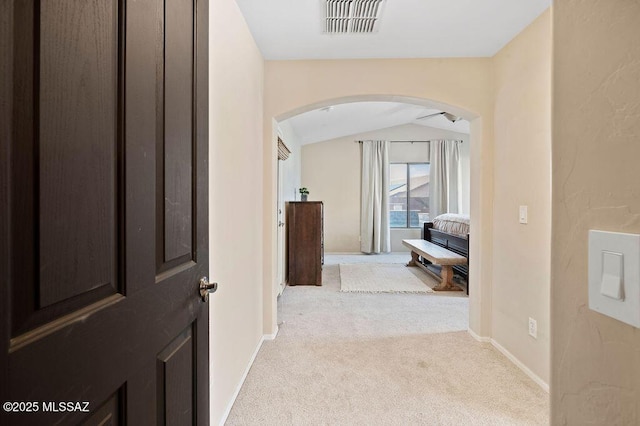 hall with lofted ceiling and light carpet