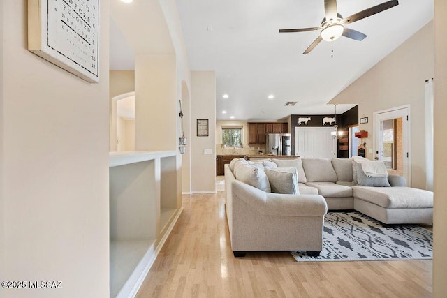 living room featuring ceiling fan, lofted ceiling, and light hardwood / wood-style floors