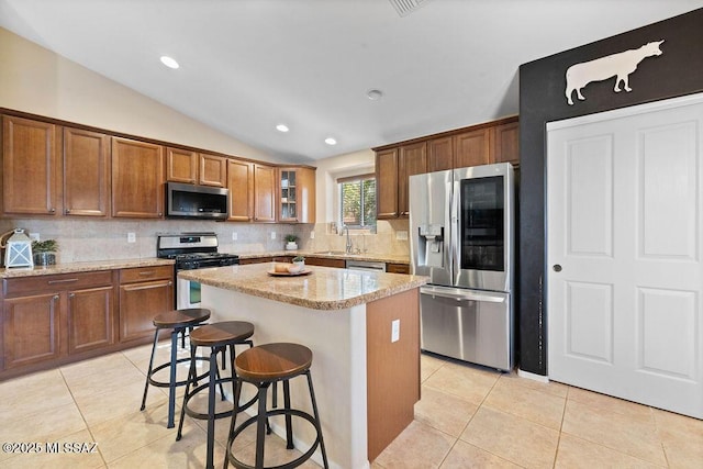 kitchen featuring sink, vaulted ceiling, a kitchen breakfast bar, a kitchen island, and stainless steel appliances