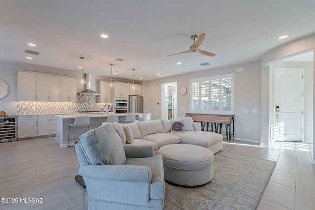 living room with ceiling fan, beverage cooler, sink, and light hardwood / wood-style flooring