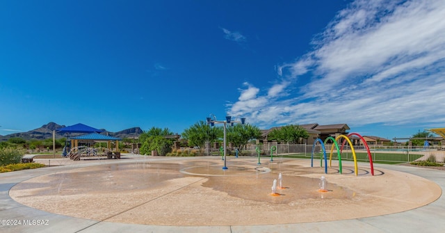 surrounding community featuring a playground, a gazebo, and a mountain view