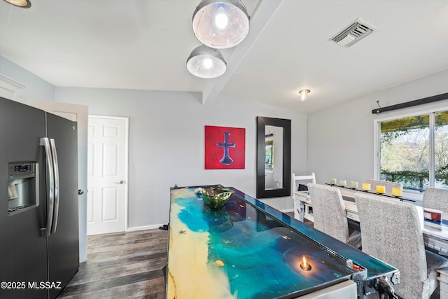 dining space with dark wood-type flooring and vaulted ceiling with beams