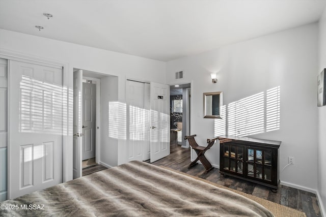 bedroom with dark hardwood / wood-style flooring and two closets