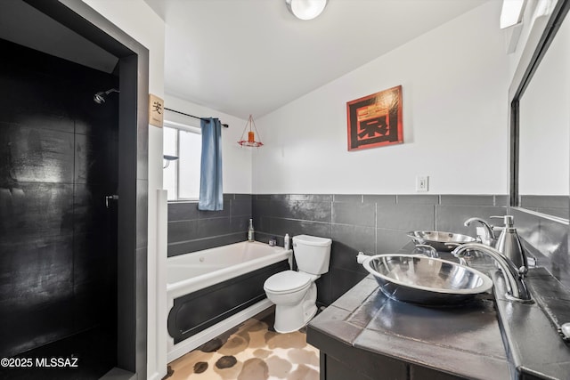 full bathroom with tile walls, sink, toilet, and separate shower and tub