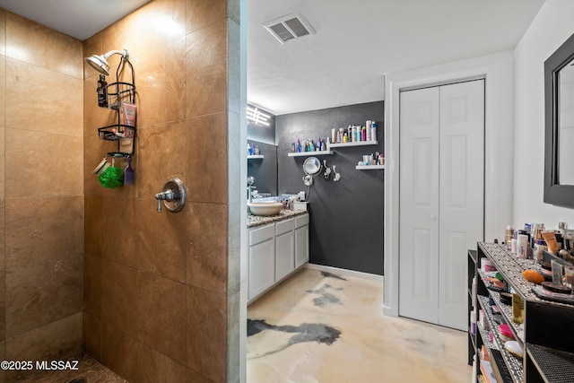 bathroom featuring vanity, concrete flooring, and a tile shower