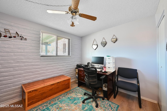 home office with hardwood / wood-style flooring, ceiling fan, and a textured ceiling