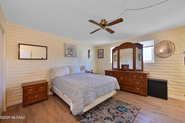 bedroom featuring lofted ceiling, light hardwood / wood-style floors, and a textured ceiling