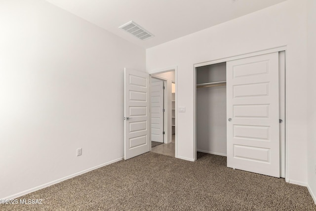 unfurnished bedroom with dark colored carpet and a closet