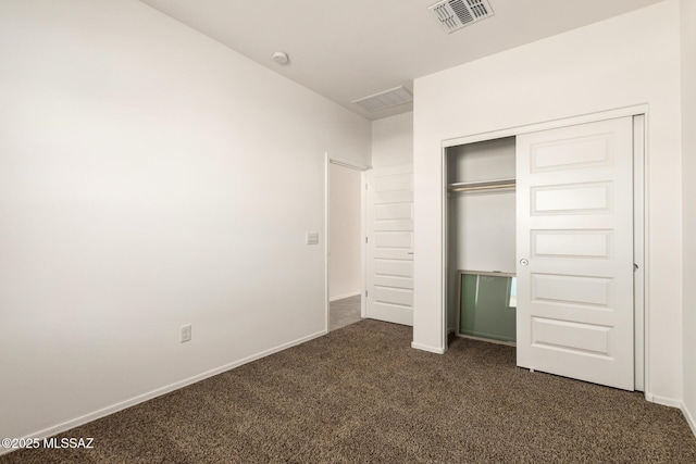 unfurnished bedroom featuring dark carpet and a closet