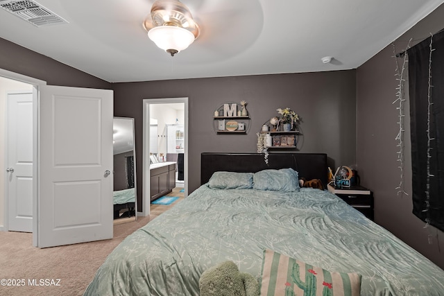 bedroom with light colored carpet and ensuite bath