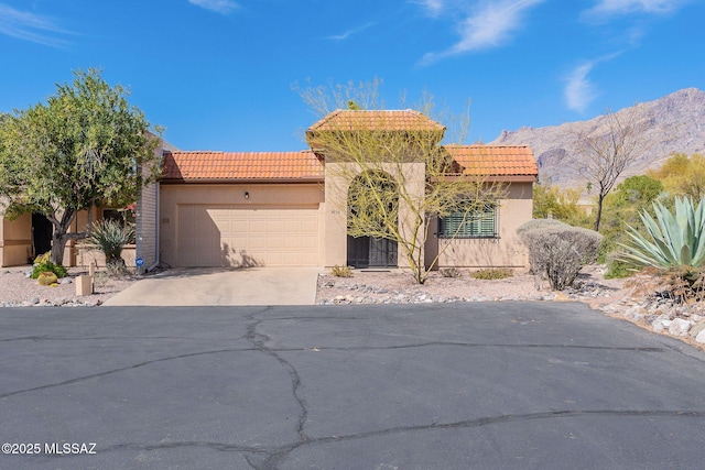 mediterranean / spanish-style home with an attached garage, a tile roof, concrete driveway, and stucco siding